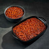 Baked beans in a bowl and a dish on a dark surface