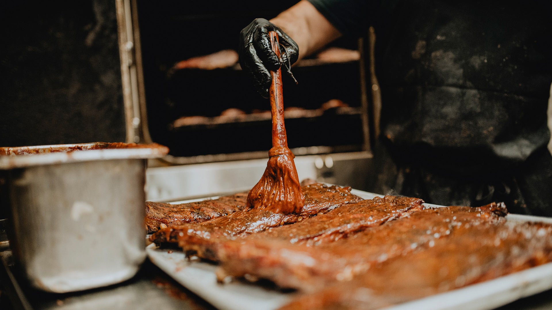 Pit master brushing barbecue meat with sauce