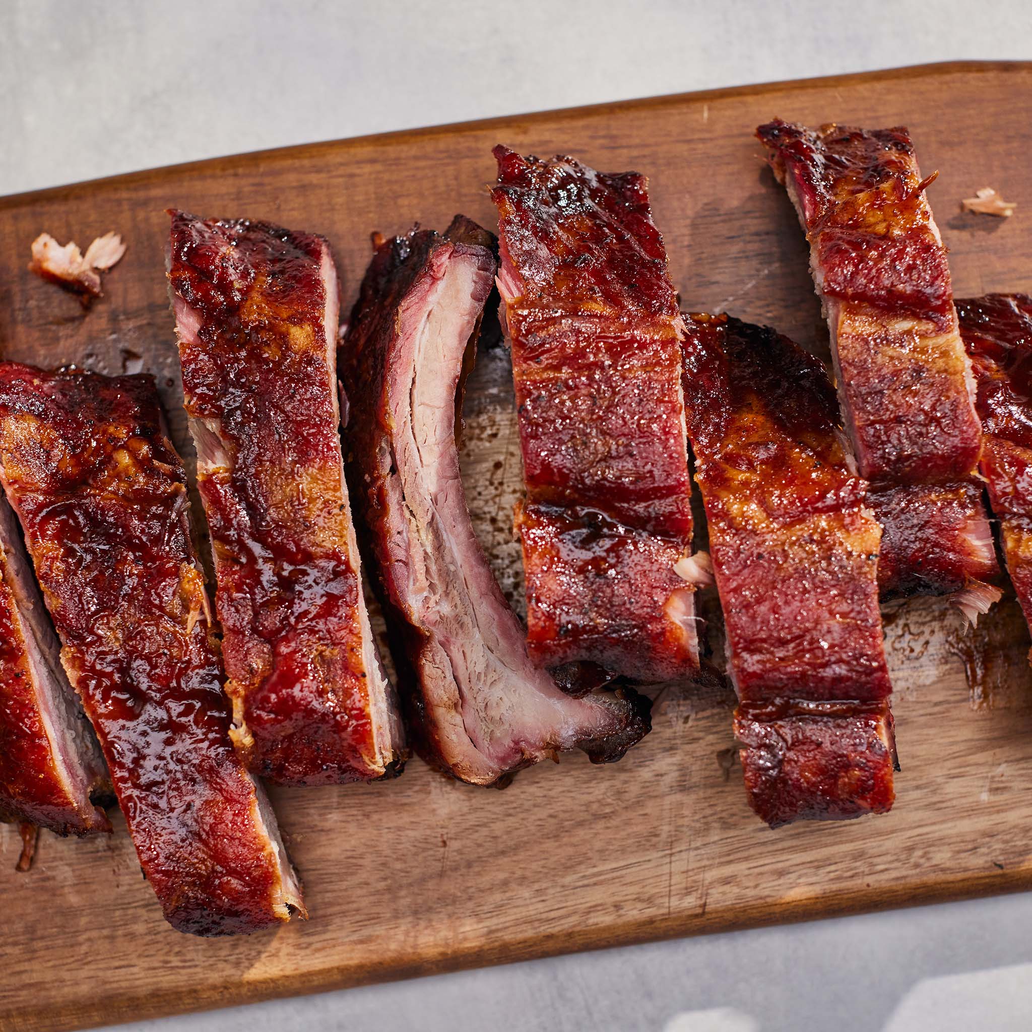 Sliced ribs on a wooden cutting board with a neutral background