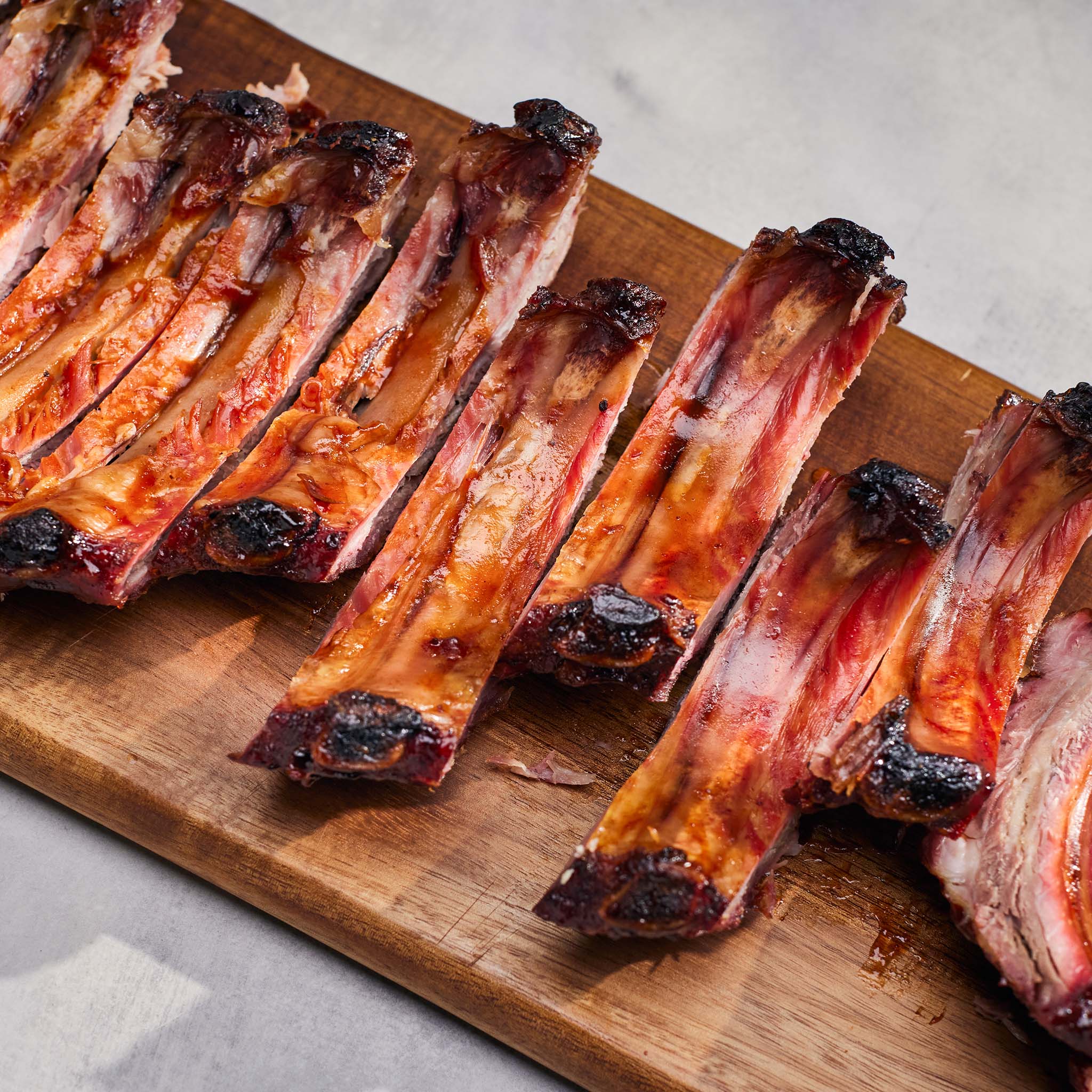 Grilled ribs on a wooden cutting board with a neutral background