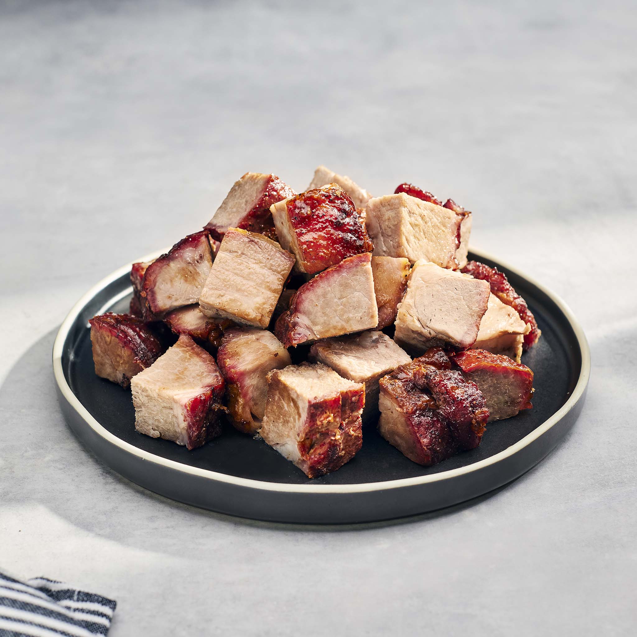 Plated dish of cubed roasted pork on a gray background