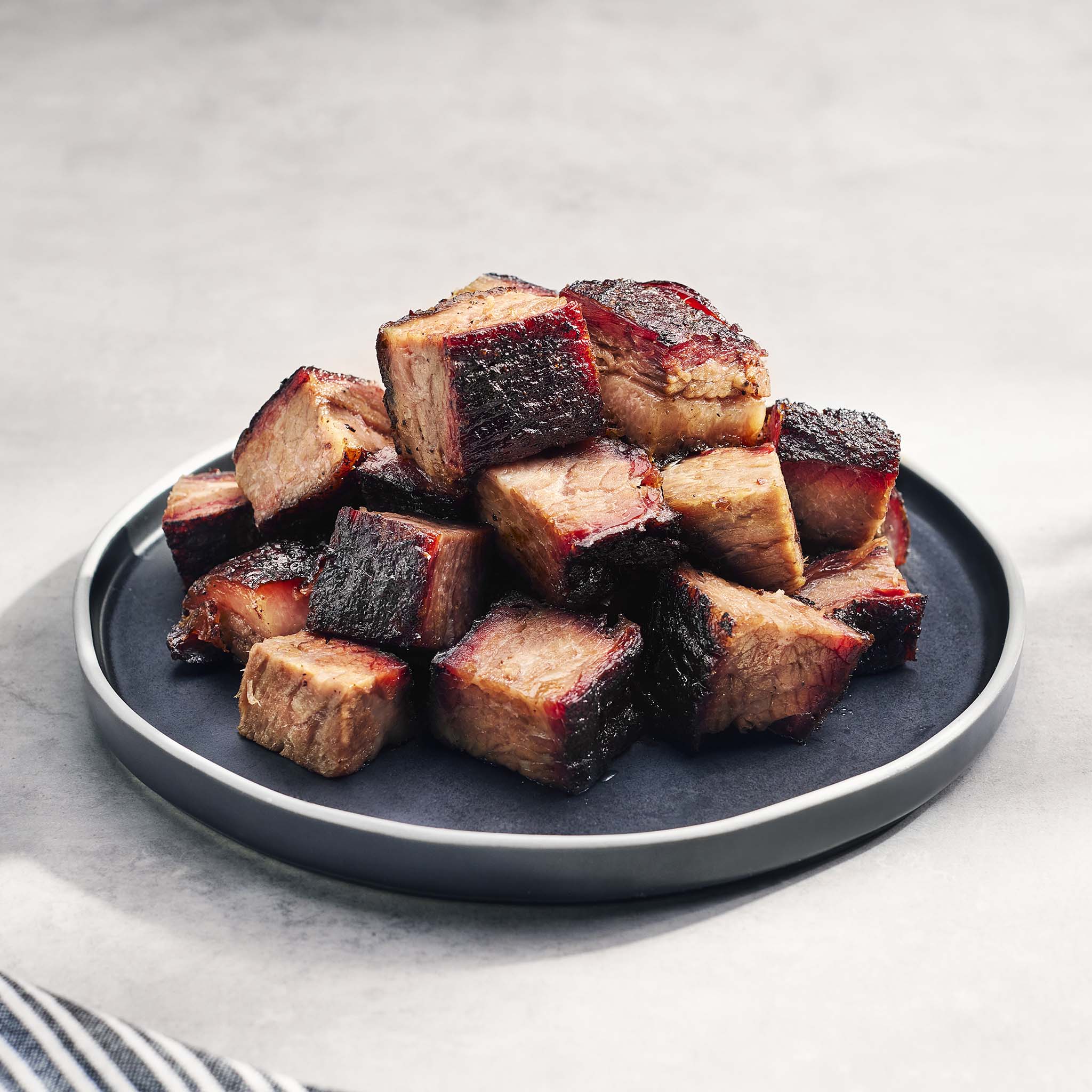 Beef burnt ends on a dark plate with a light background