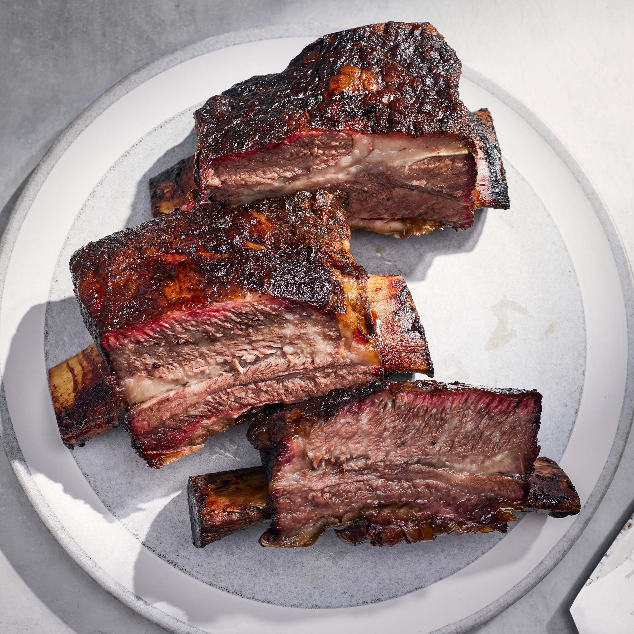Braised ribs on a white plate with a gray background