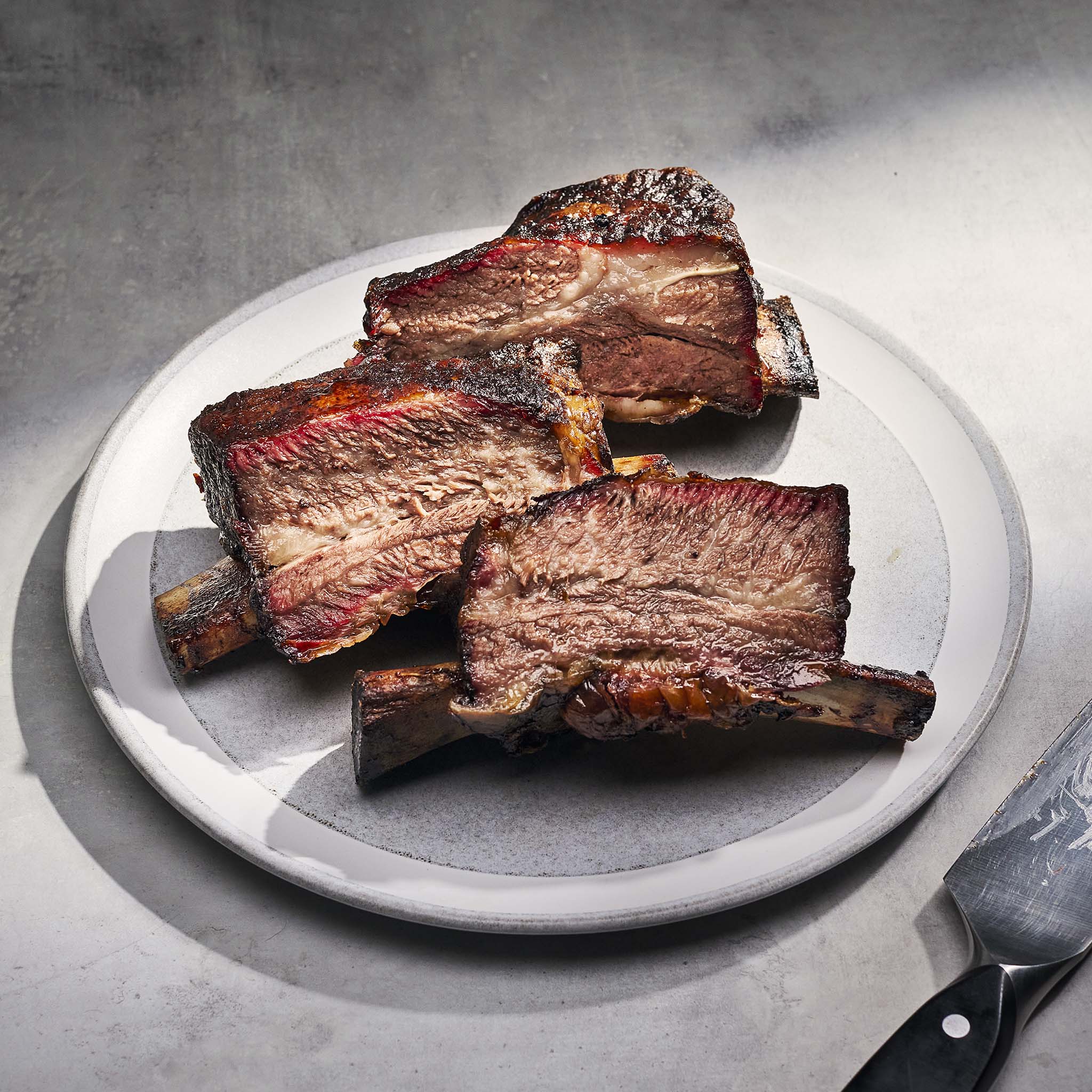 Braised ribs on a white plate with a gray background