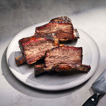 Braised ribs on a white plate with a gray background