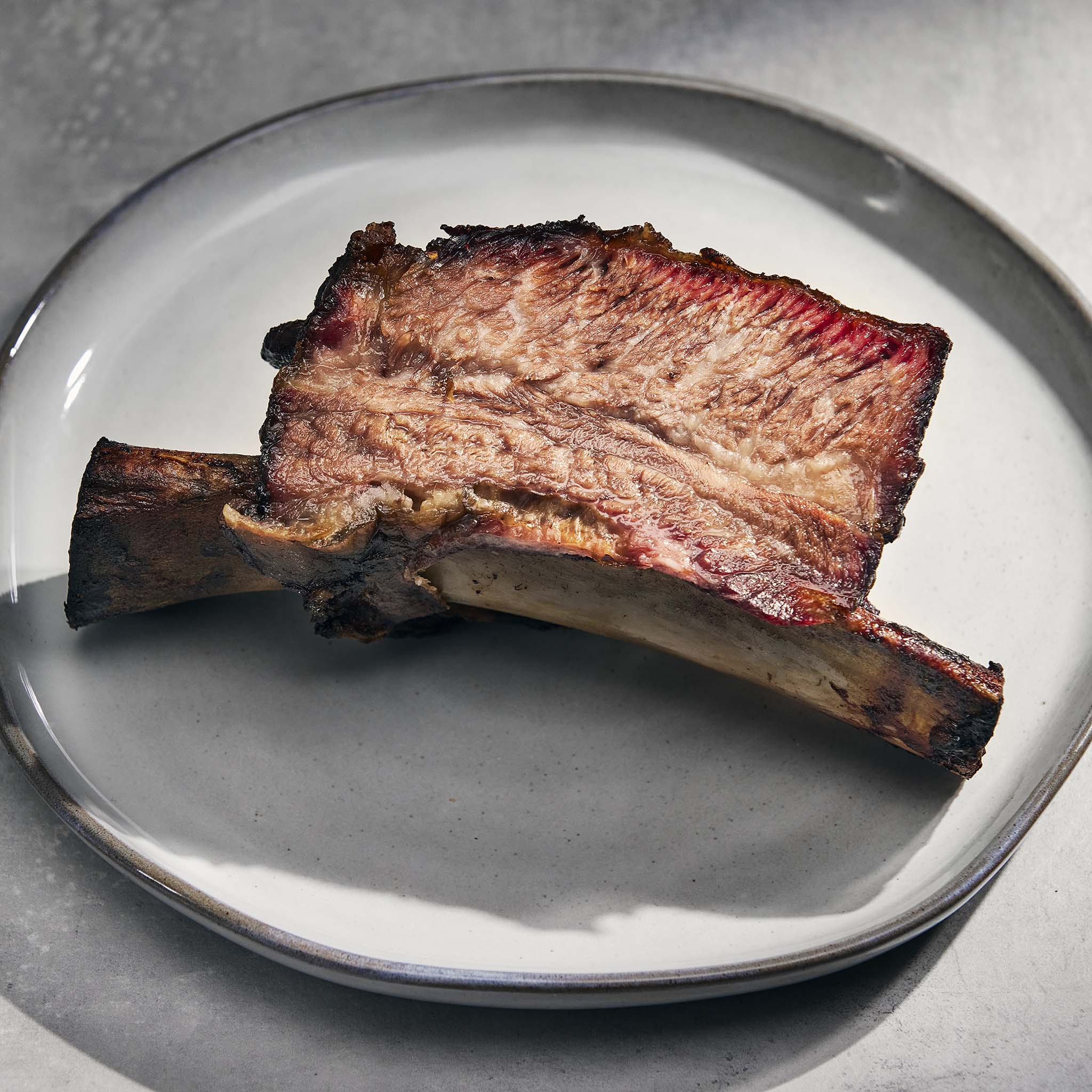 Grilled rib on a white plate with a gray background