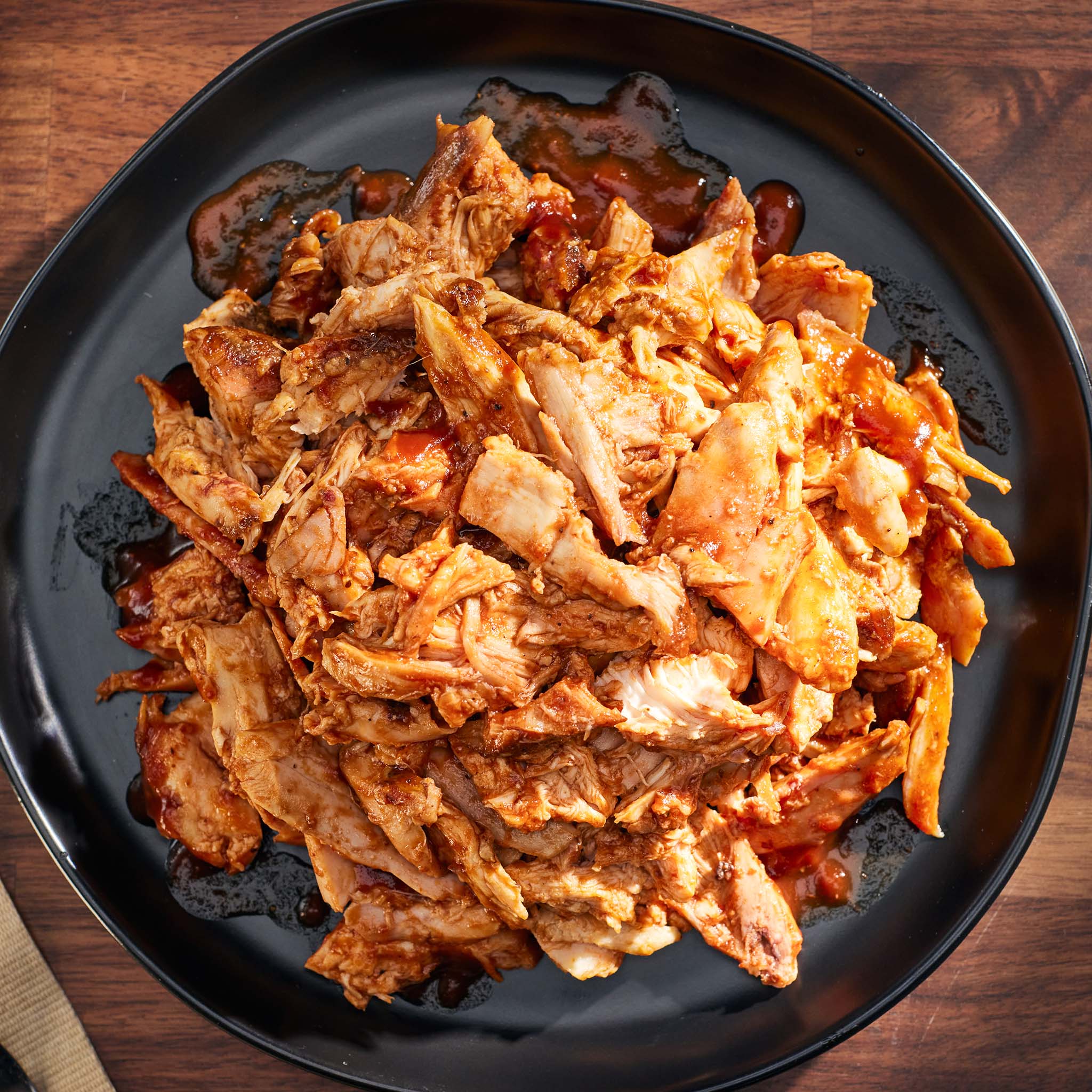 Shredded chicken with red sauce on a black plate