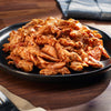 Plated dish of shredded chicken with a wooden background