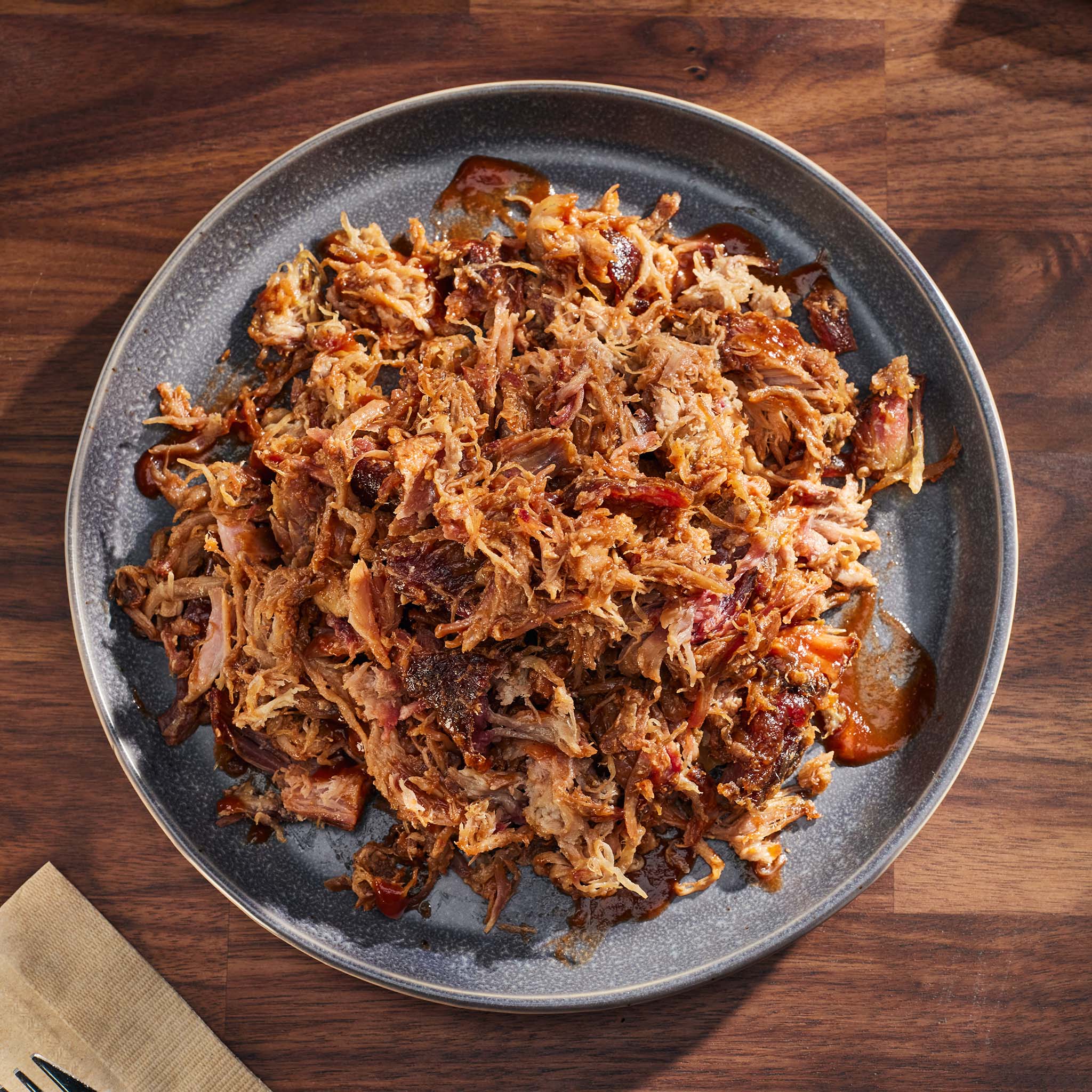Shredded pulled pork on a gray plate with a wooden background