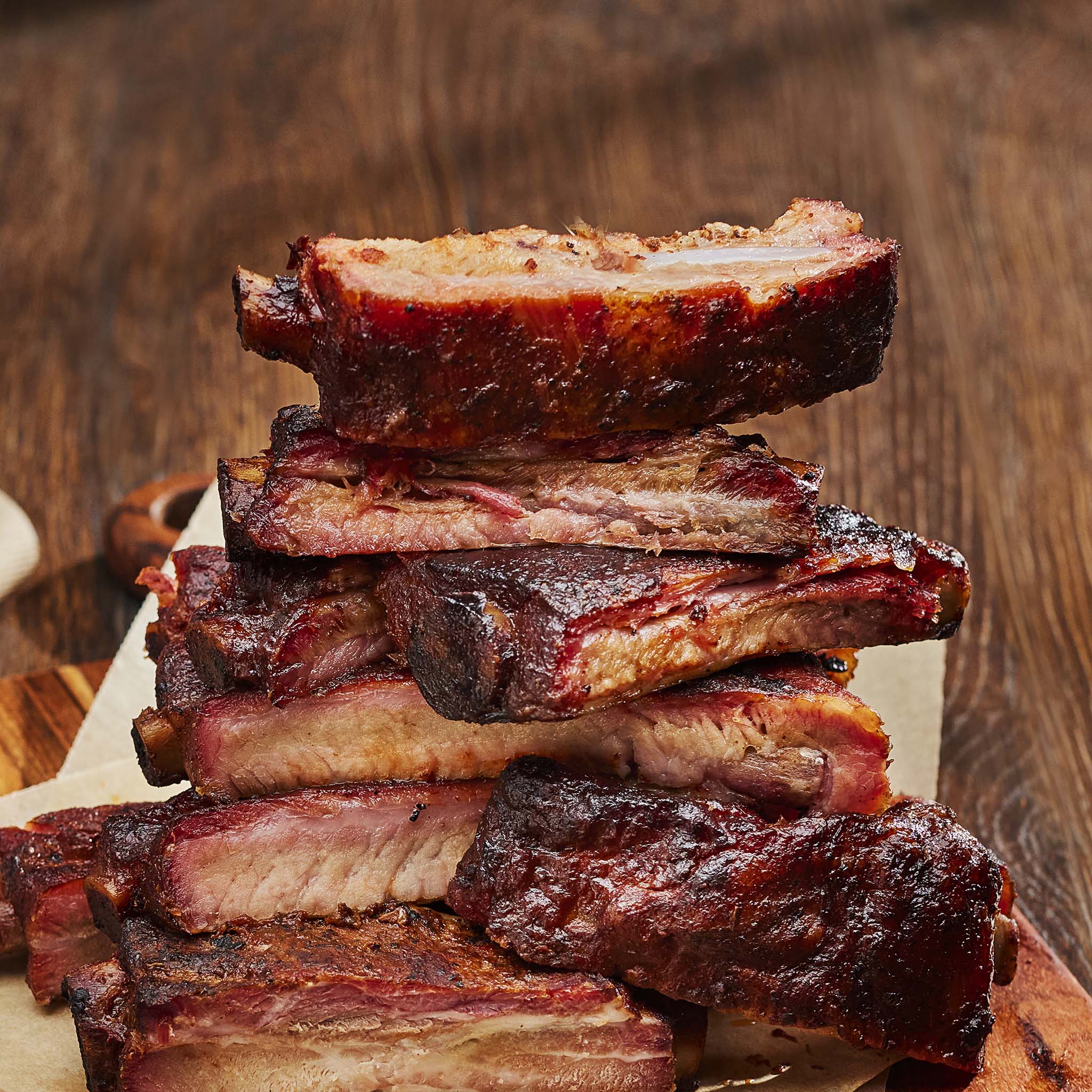 Stack of ribs on a wooden cutting board with a blurred wooden background