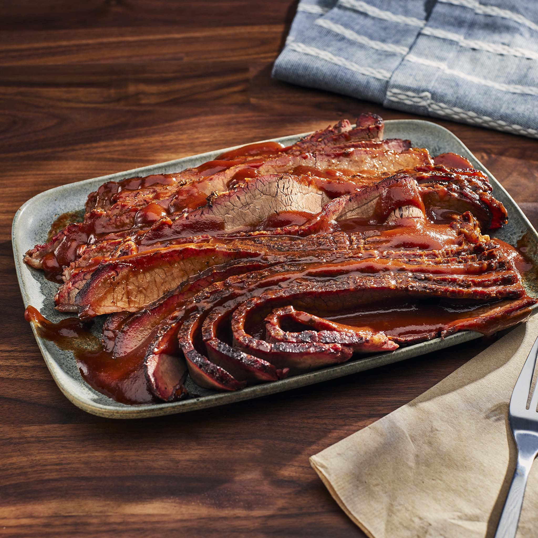 Sliced brisket on a platter with a wooden background