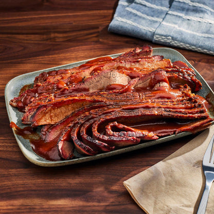 Sliced brisket on a platter with a wooden background