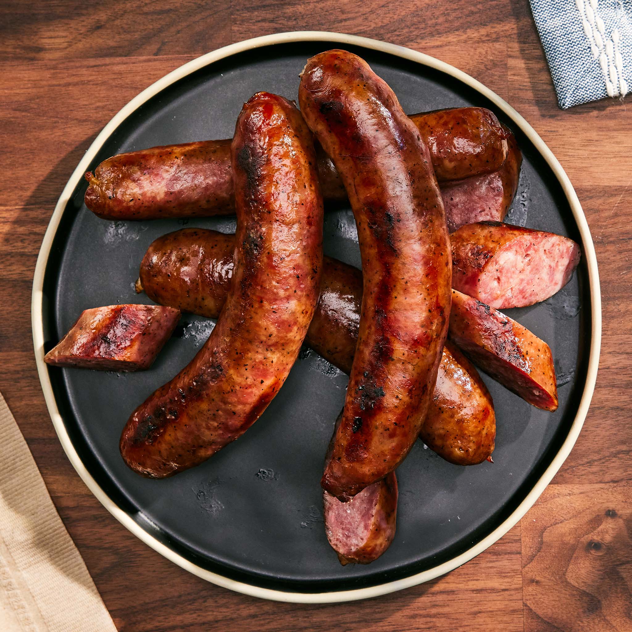 Grilled sausages on a black plate with a wooden background