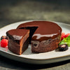 Triple chocolate brownie with a slice cut out on a plate with berries
