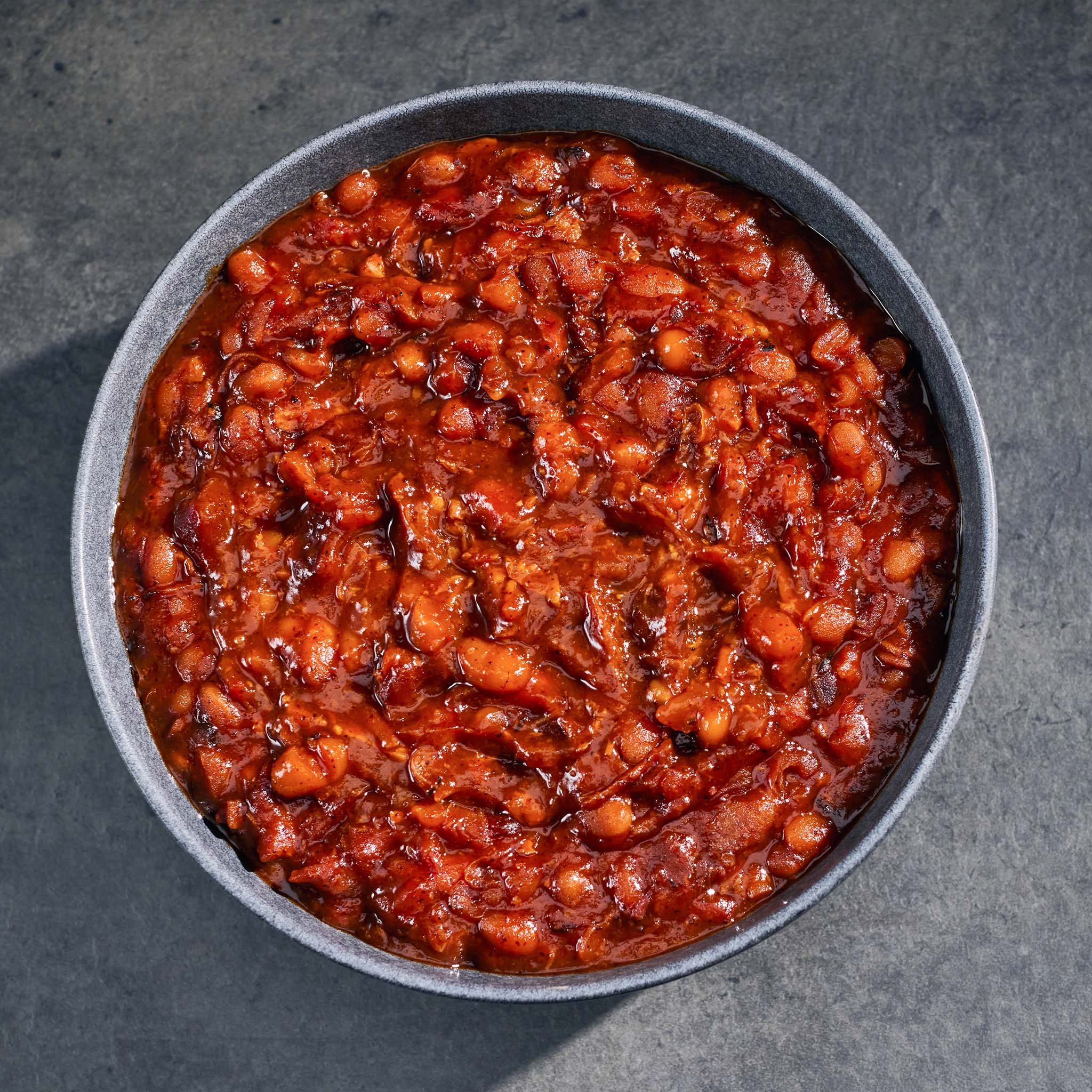 Bowl of baked beans on a dark surface