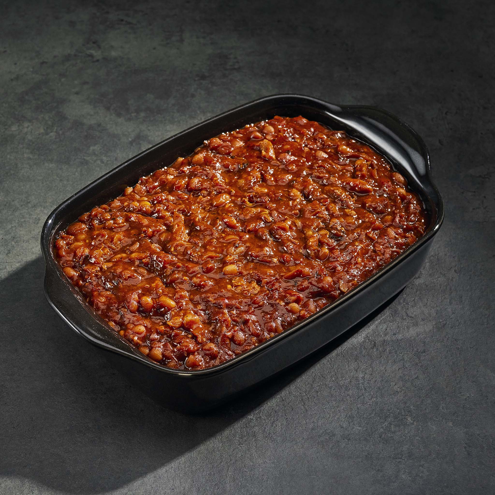 Baked dish in a black rectangular baking pan on a dark surface
