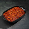 Baked dish in a black rectangular baking pan on a dark surface
