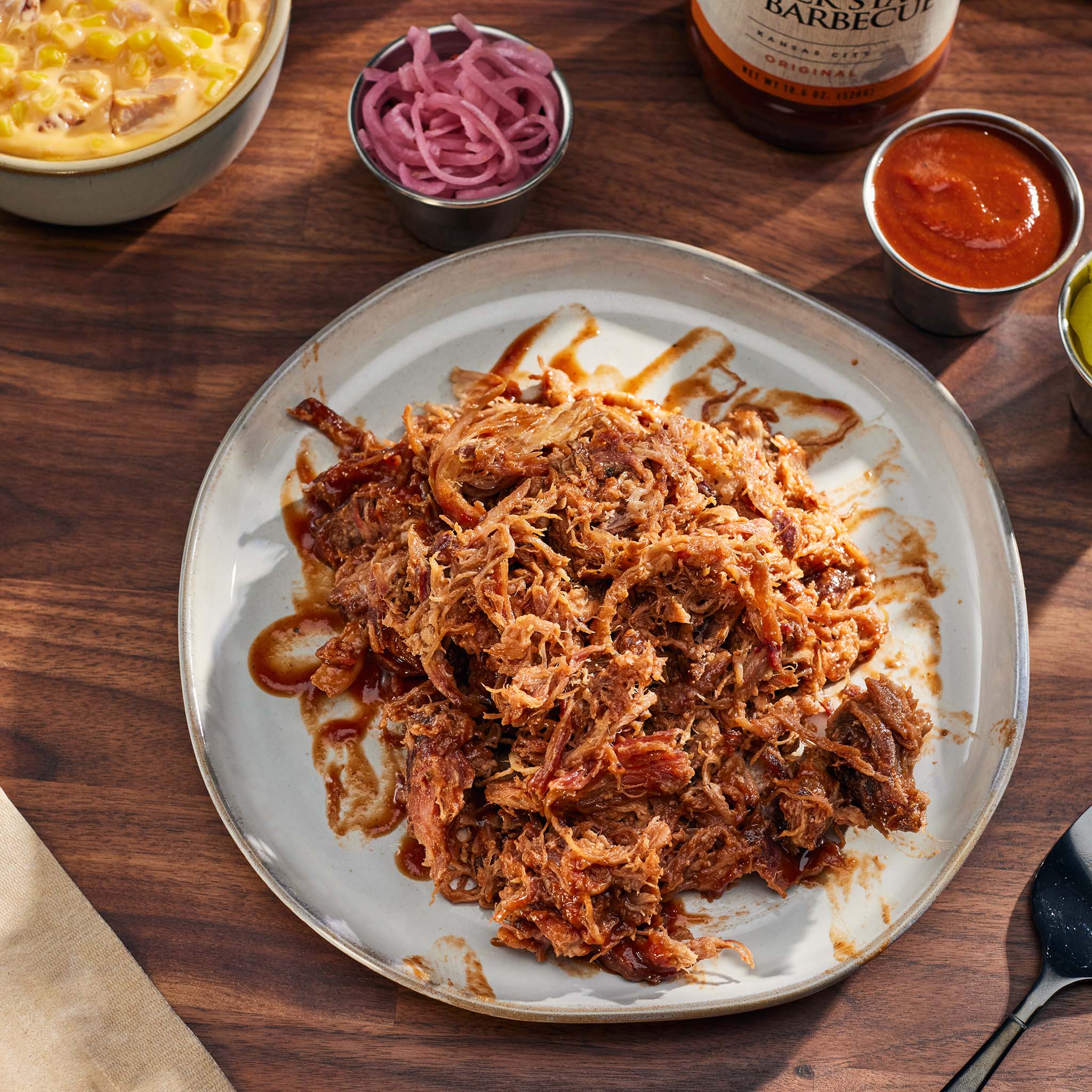 Plated pulled pork with various condiments on a wooden table