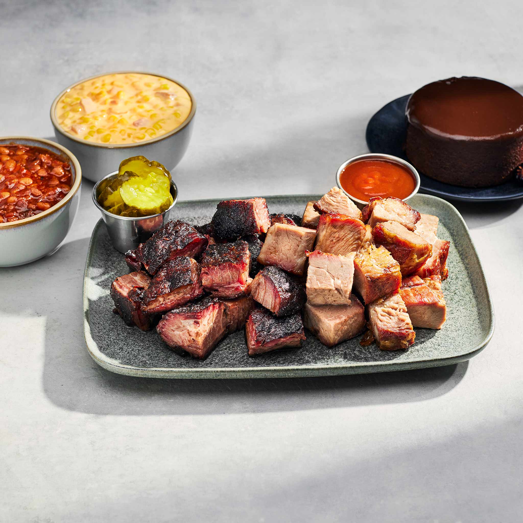 Plated barbecue meat with sides on a gray surface