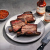 Bbq ribs on a plate with Jack Stack Barbecue products on a gray surface