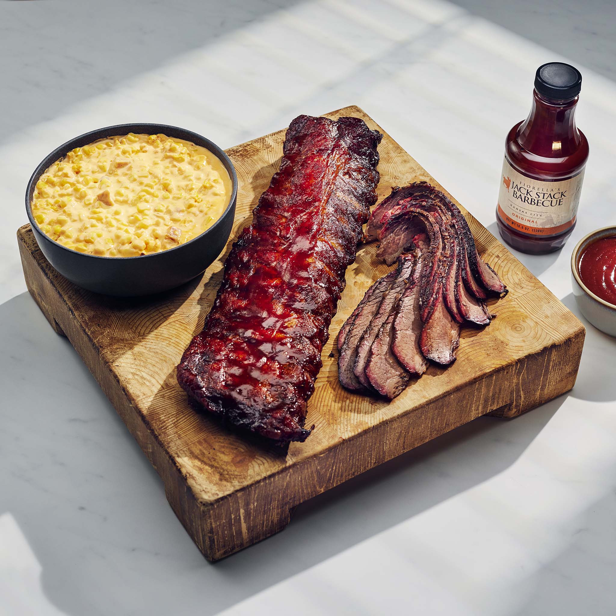 Barbecue ribs on a wooden board with corn and barbecue sauce, on a light background