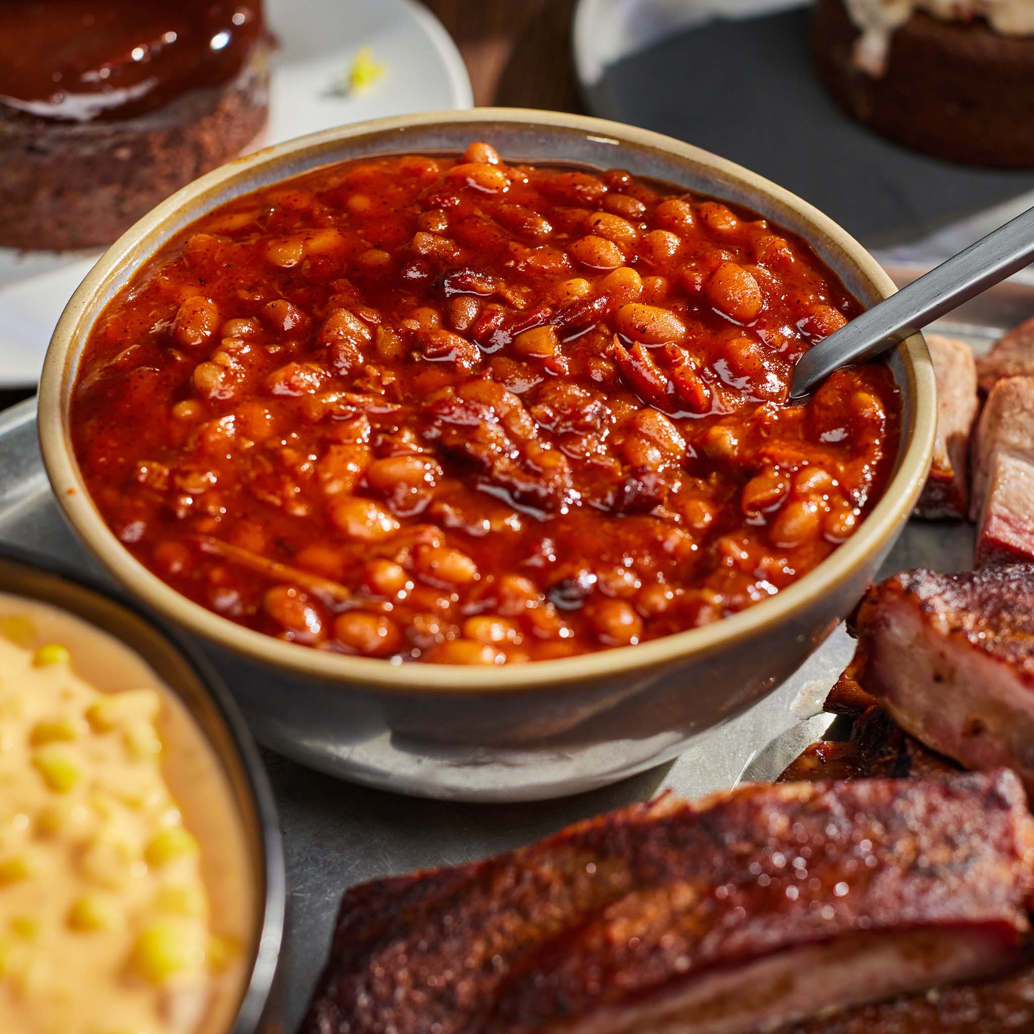 Bowl of baked beans on a table with other food items