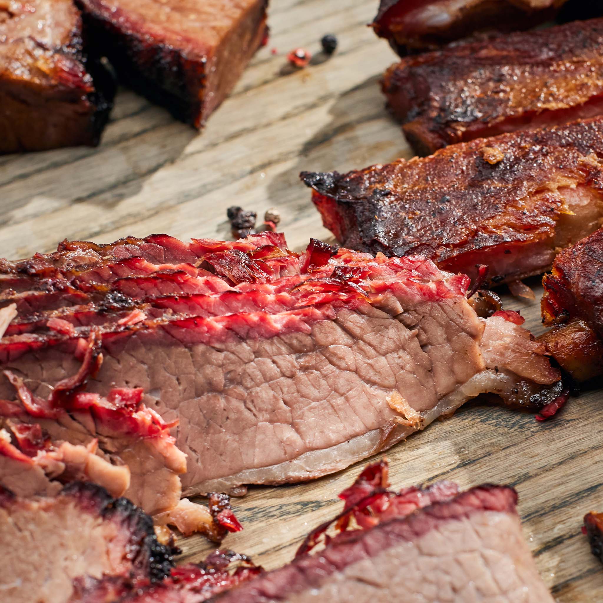 Close-up of sliced beef with charred exterior on a wooden surface