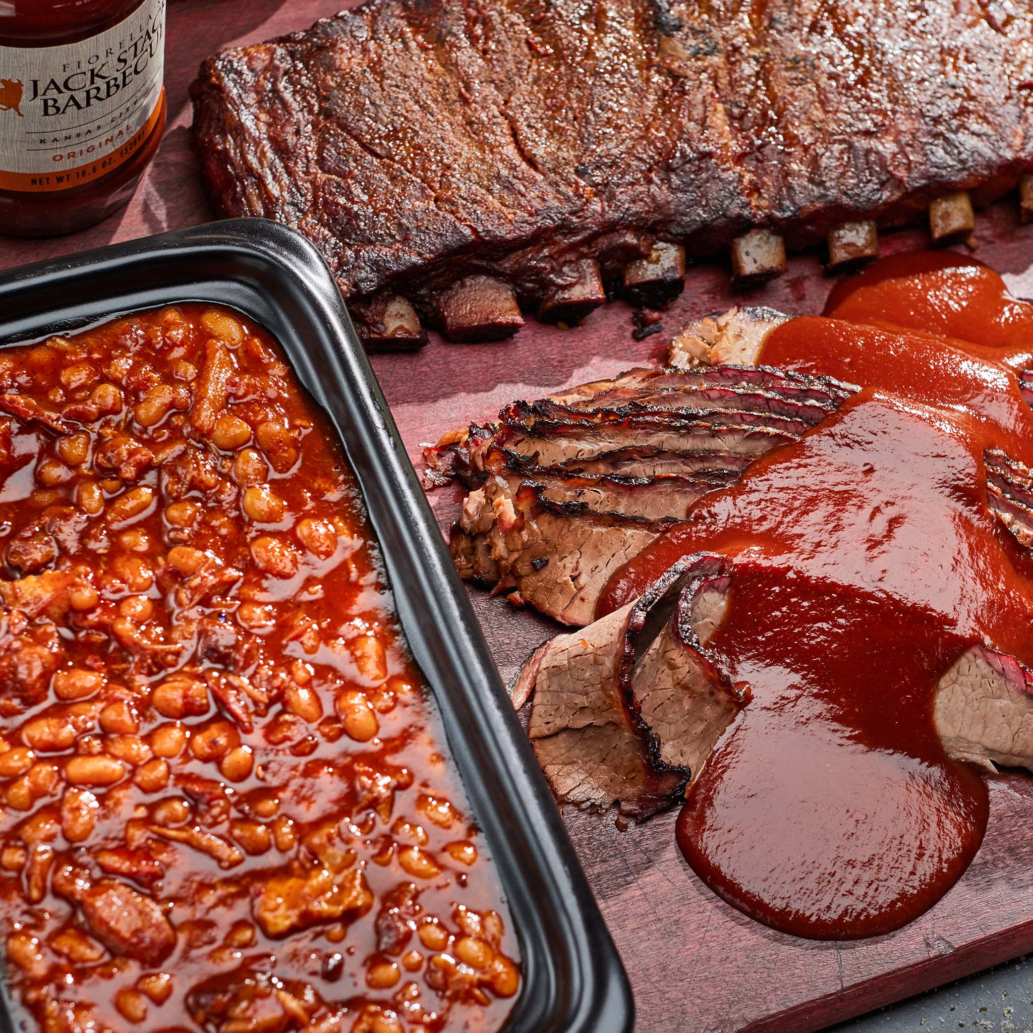 Ribs and baked beans with a bottle of Jack Daniel's on a wooden surface