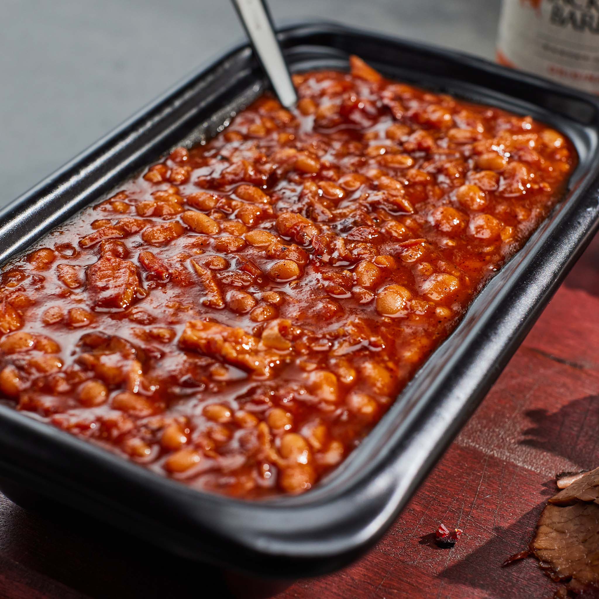 Baked beans in a black tray on a wooden surface