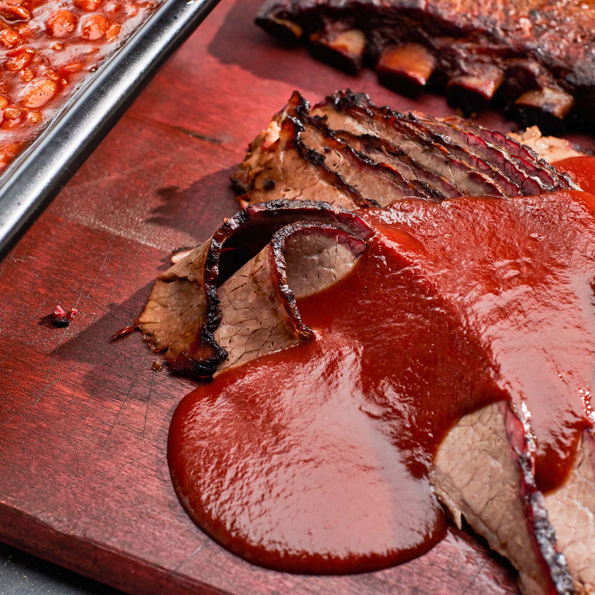 Sliced beef with red sauce on a wooden cutting board