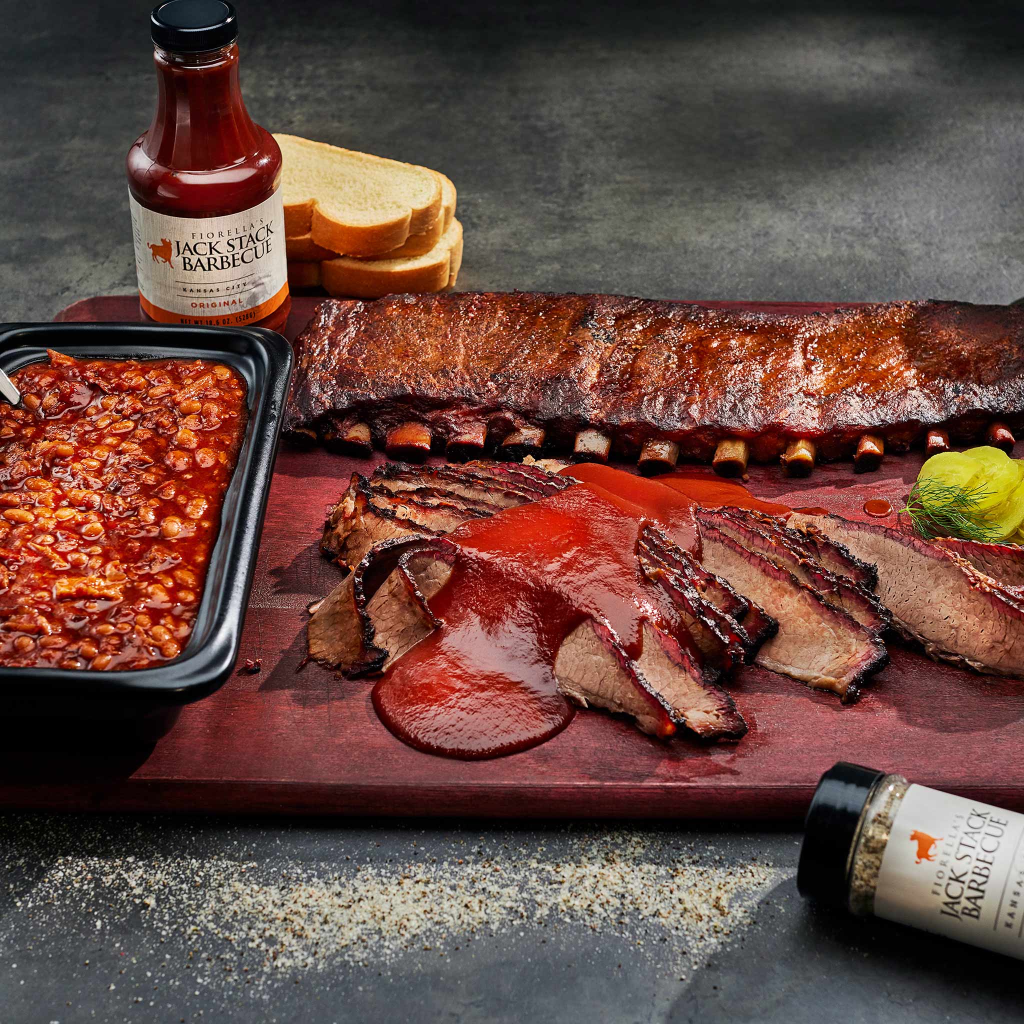 Sliced barbecue meat on a cutting board with Jack Daniel's barbecue sauce and ingredients.