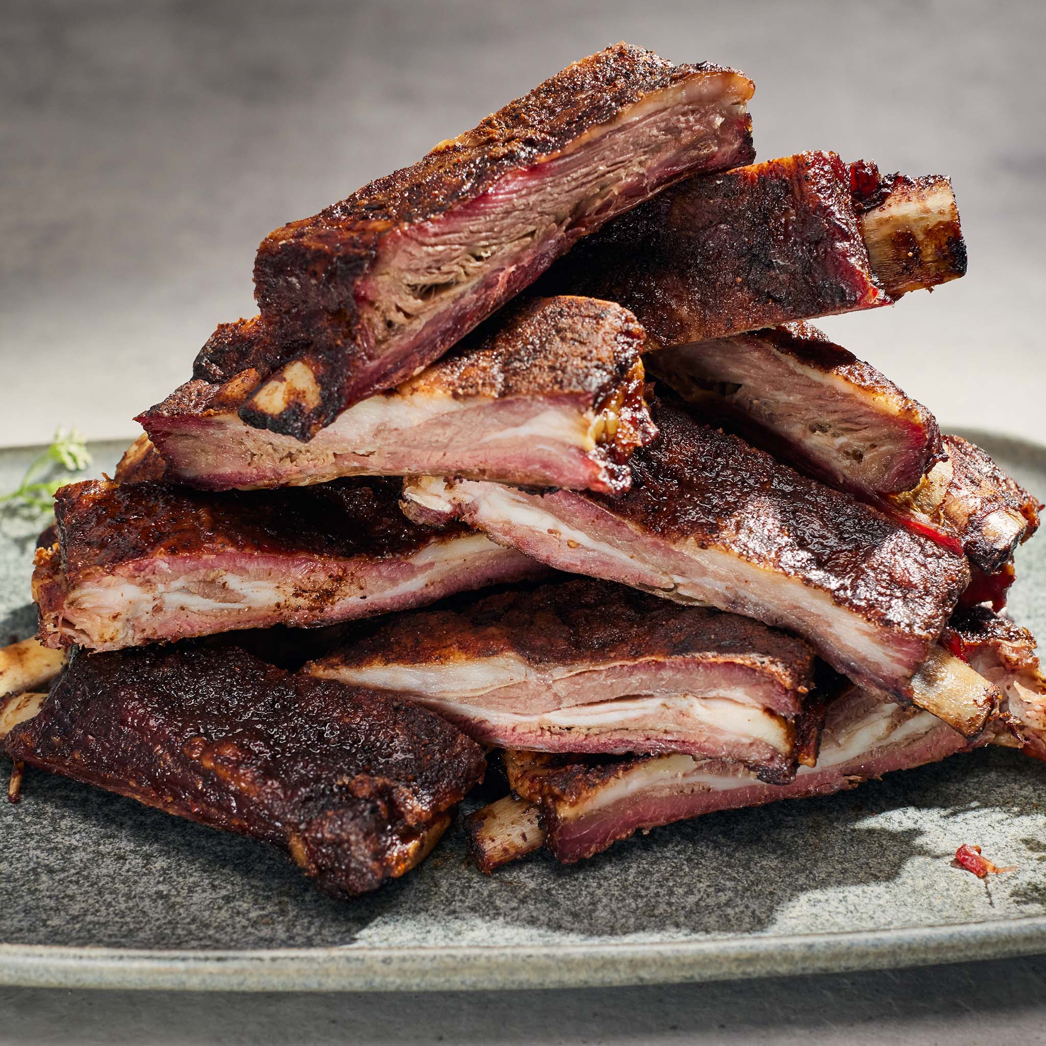 Stack of ribs on a gray plate with a neutral background