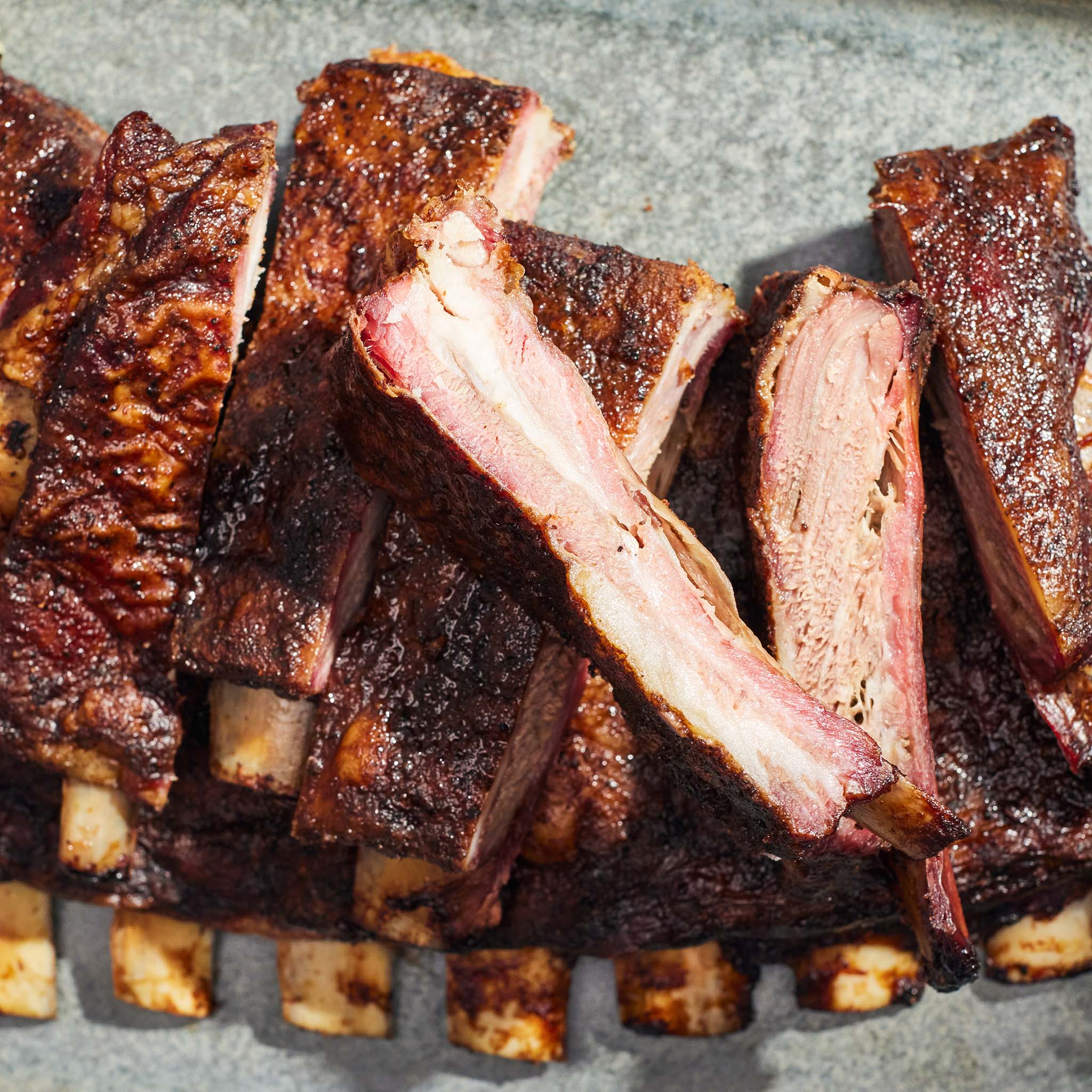 Sliced ribs with a crispy, browned exterior on a stone surface