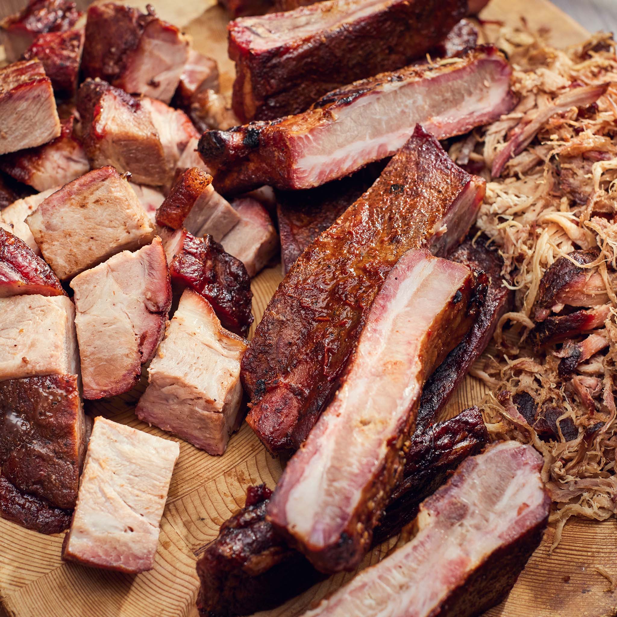 Assorted smoked meats on a wooden cutting board