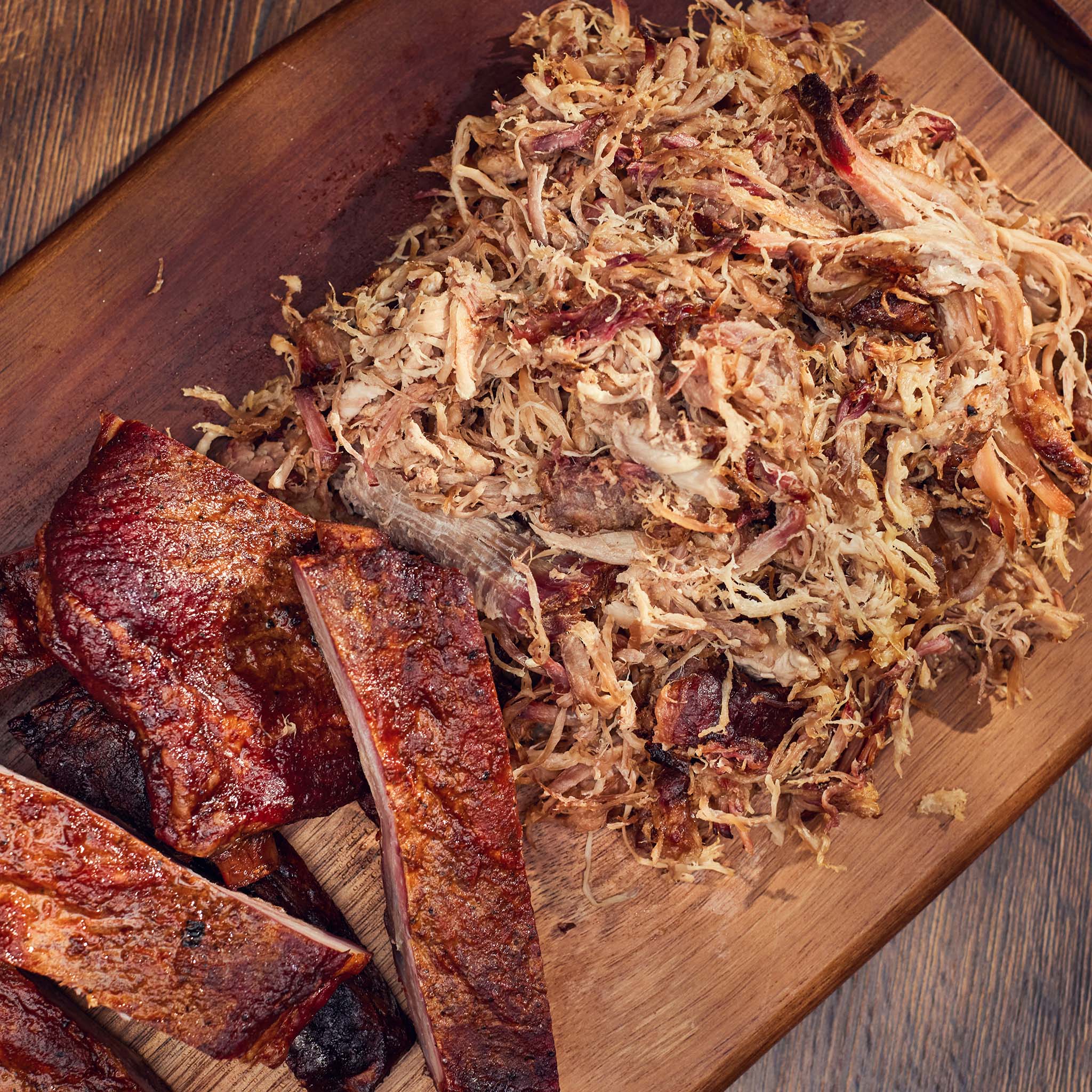 Shredded meat and ribs on a wooden cutting board