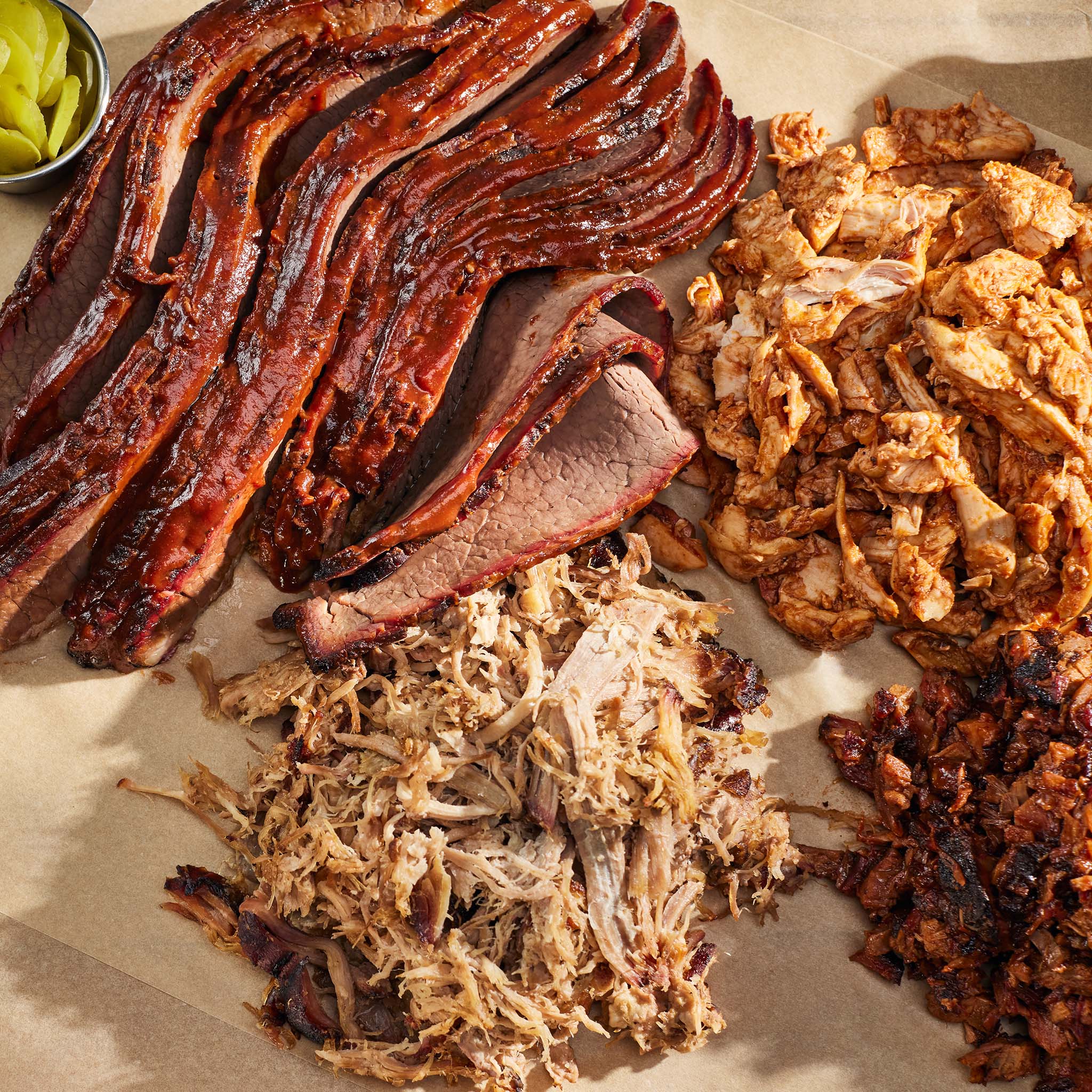 Assorted smoked meats including ribs, pulled pork, and chicken on a wooden surface.
