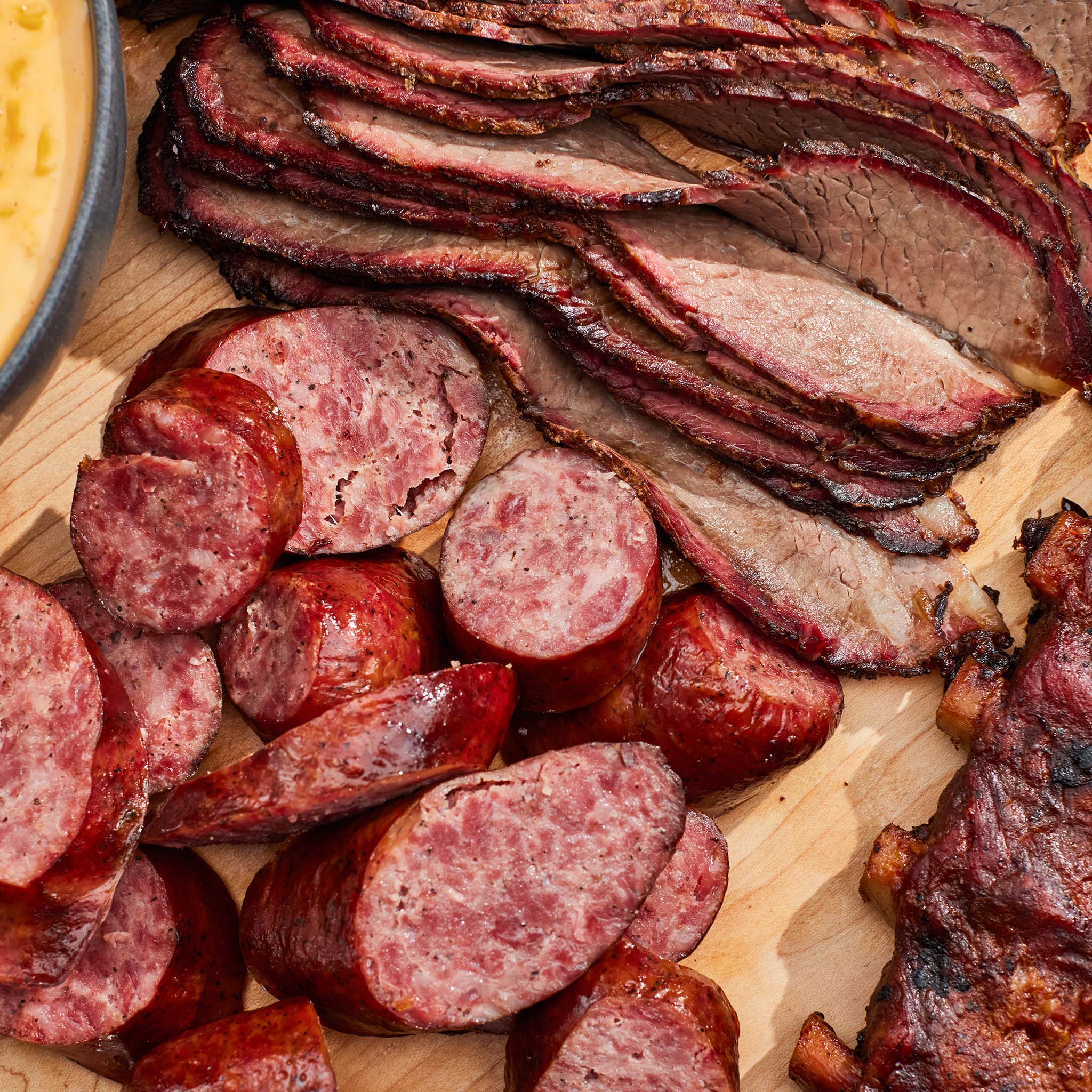 Platter of sliced cured meats including salami and pepperoni on a wooden board.