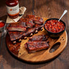 Wooden platter with ribs and baked beans, Jack Daniel's BBQ sauce bottle in the background.