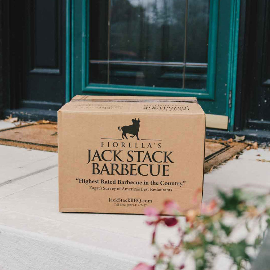 Cardboard box from Fiorella's Jack Stack Barbecue on a porch with flowers in the foreground.